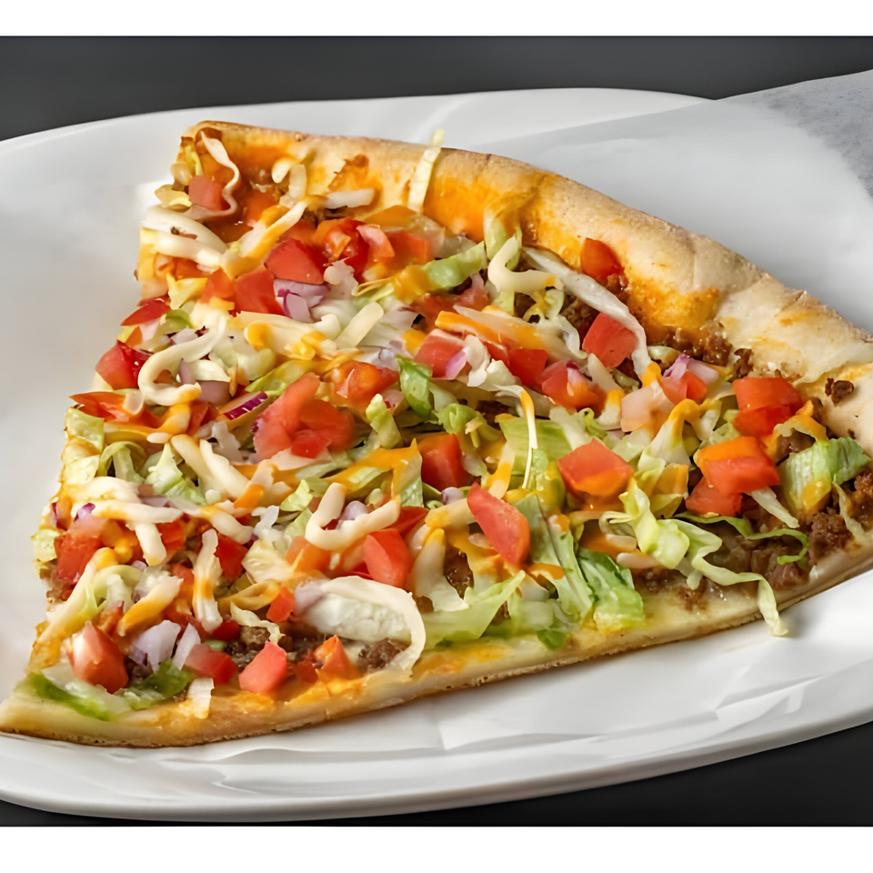 A slice of taco pizza with ground beef, lettuce, tomatoes, cheese, and a creamy sauce.