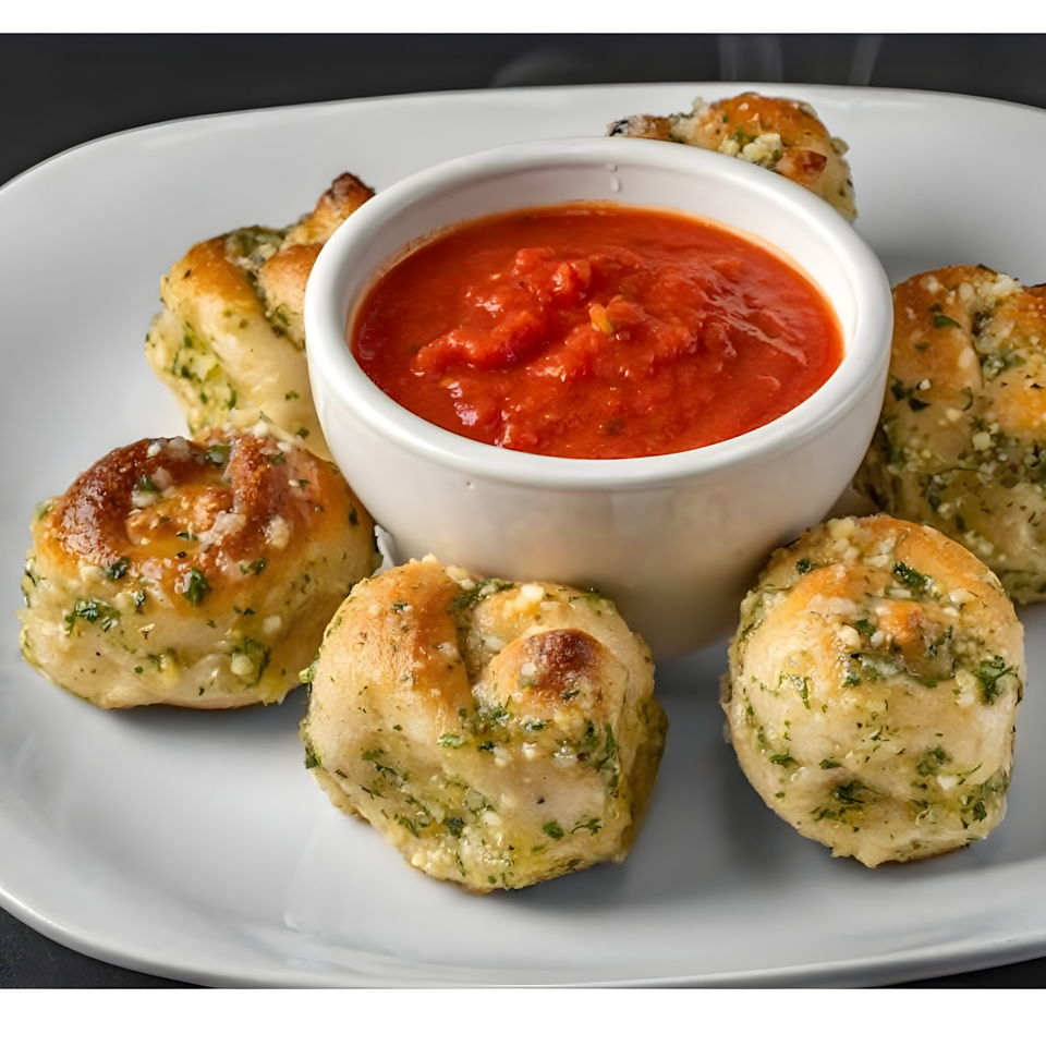 Bella Villa Pizza & Restaurant's garlic knots, golden brown with herbs and cheese, served with marinara sauce.