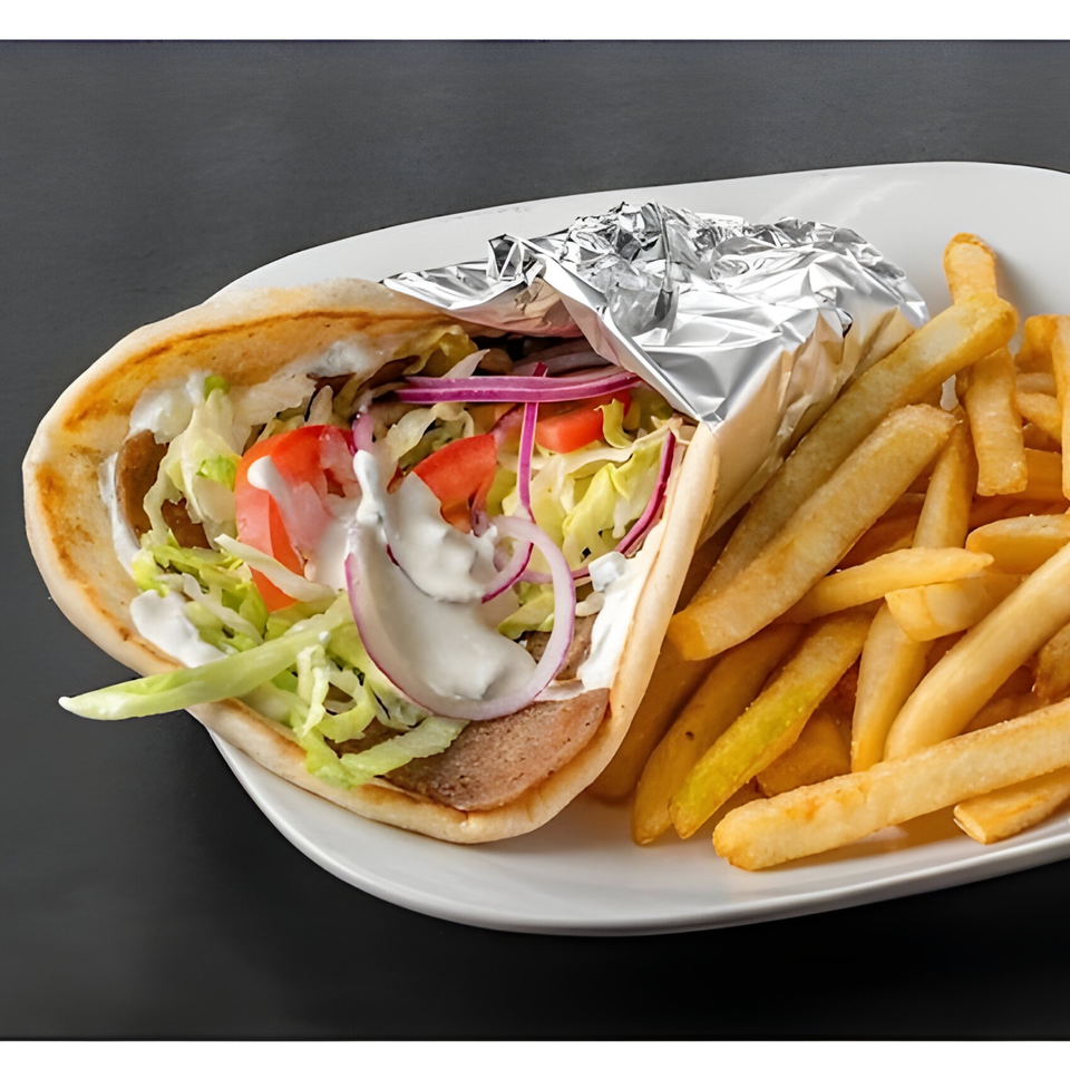 A gyro with meat, lettuce, tomatoes, red onions, and white sauce, served with french fries.