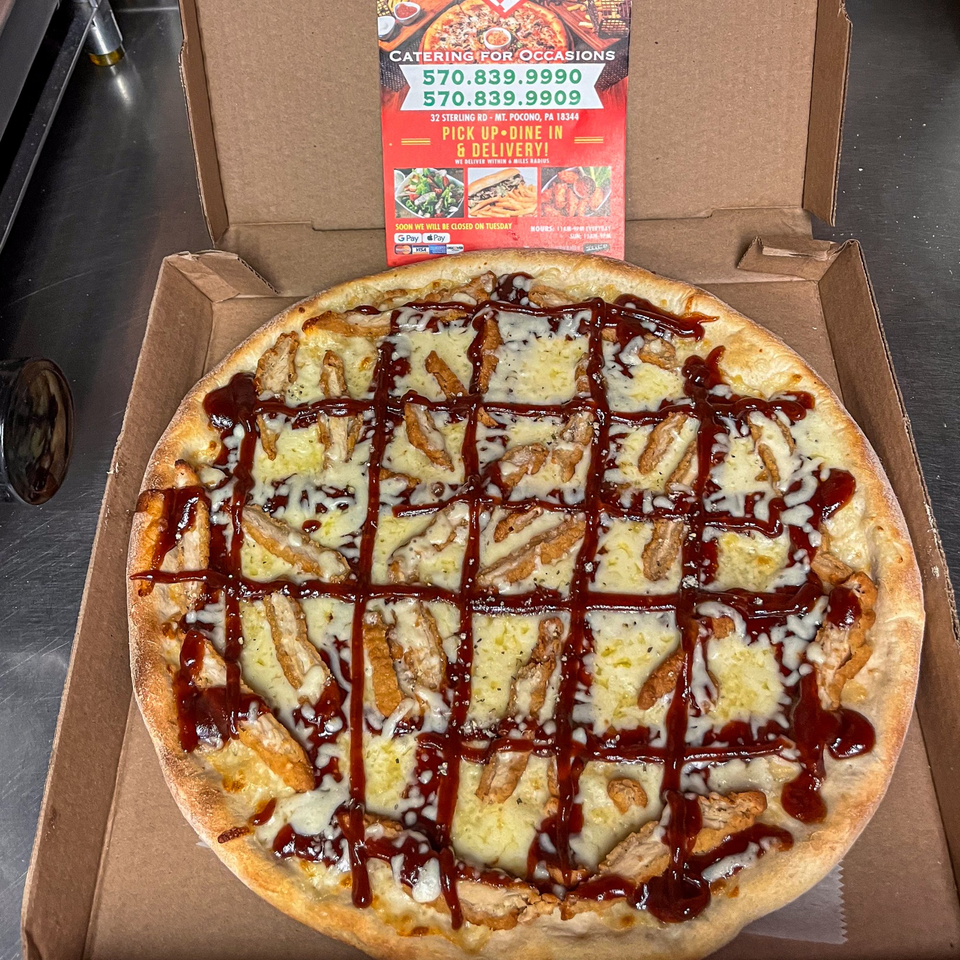 A BBQ chicken pizza with melted cheese and a drizzle of sauce, in a cardboard box.